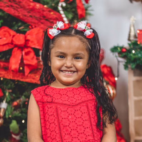 Hispanic girl by christmas tree